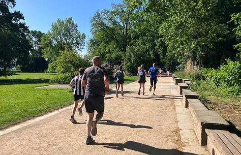 Runners on wide beige gritty paths under a blue sky