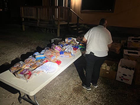Jon Pantoja, Edward Hood, Daniel Paasch, and Ginni Stalker stand in front of their food distribution tables