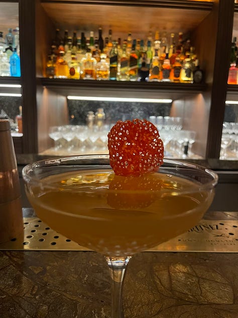 First image: line of suits in a windowcase. Second image: curated bookcase. Third image: a cocktail in a coupe.