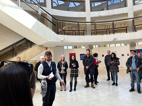 Several people standing and wandering in a circular gallery space.