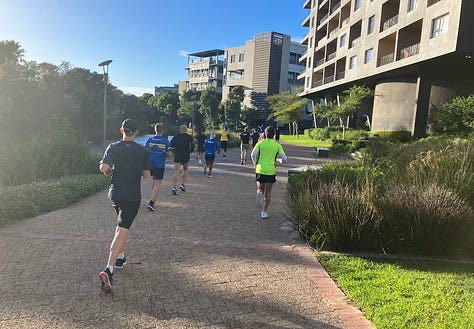 Canal on the left of the path, runners ahead on the course