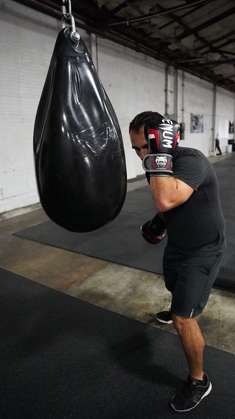 Brian hitting a punching bag at the back of a gym.