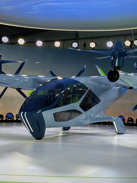 The Supernal S-A2, a sleek aircraft on a round stage surrounded by lights. One photo shows a green-lit interior with four passenger seats.