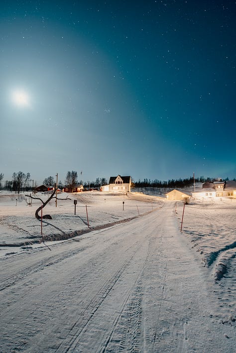 Winter landscape of Norway at night, containing the aurora borealis and ice covered roads between Tromso and Senja Island