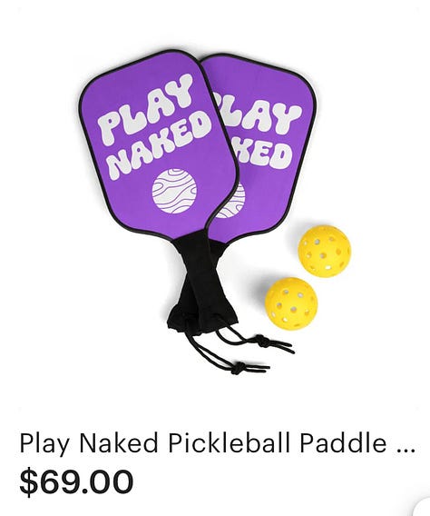 This ad for the Planet Nude Gift Shop showcases a new design with the phrase “Live Naked Die Happy” in a bold, retro-style script. The text is accompanied by a simple, stylized illustration of two nude figures reclining on a soft, wavy background in shades of purple. The ad features three product images: A black cotton tote bag with the “Live Naked Die Happy” design in white. A die-cut sticker with the same design, featuring a white border around the text and illustration. A white unisex t-shirt displaying the design prominently on the chest. Each product is listed with its price: Tote bag: $29.00 Sticker: $10.00 T-shirt: $29.00