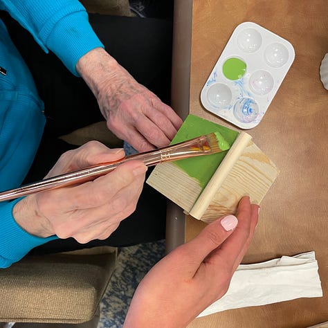 Hands, young and old, arrange bouquets and paint wooden birdhouses together. 