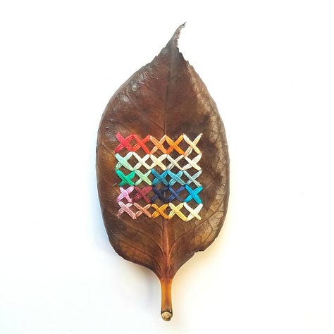 three leaves with thread woven or stitched on.