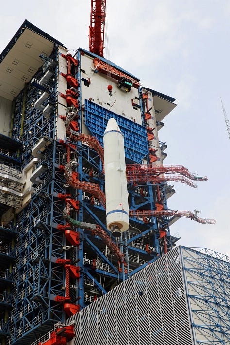 The third-stage of the rocket undergoing hardware installation, one of the boosters being lifted during stacking, and the first and second stages ahead of pre-launch operations on the launch pad.