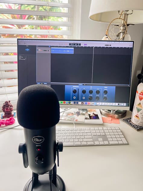 selfie photo of woman smiling in her apartment; selfie photo of three friends under a beach umbrella; photo of a beagle-King Charles Cavalier Spaniel mix dog looking down at the floor, taken from dog's eye level; photo of the photographer's legs and bare feet standing on thick, green blades of grass; photo of a microphone and computer screen with recording software; photo of a black and white cat lounging on a paved path of lush garden in the backyard of a building; photo of sunset at the beach with rays of pink and white and blue light over the horizon above the water; photo of cars driving in heavy traffic on a highway with billboards and buildings in the distance and white and gray clouds in the foreground and a clear blue sky in the background; wide-angle photo of a wide tan beach with the ocean in the far distance and a blue sky with white and gray swirling clouds above and a wide double rainbow over the shoreline.