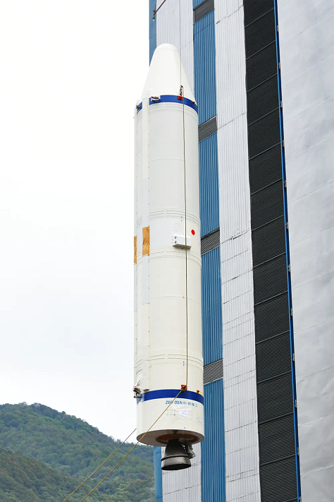 One of the Long March 3B/E's boosters being lifted during preperations, the rockets second-stage following equipment installation, and the vehicles fairing with the asteroid program's logo.