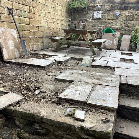 Five pictures of the patio in various stages of repair. First being pressure washed, second, three men is hi-vis clothing are gathered round one flag ‘discussing’ the work needed, third is a pic of lots of lifted flags and a lot of mess, fourth is he revealed steps of York stone and the relaid and regrouted old flags of many colours, the first is a picture of fags that have been regrouted, the grout is ina contrasting colour. 
