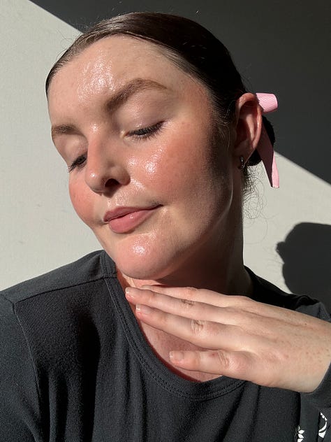 Morgan applies a cream peach blush to her cheeks and uses fingers to blend them out
