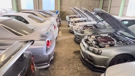 A collection of photos showing dozens of white, blue and green Nissan R34 Skyline GT-R sports cars crammed into a dimly-lit warehouse with gray walls and green support beams with a gravel floor.