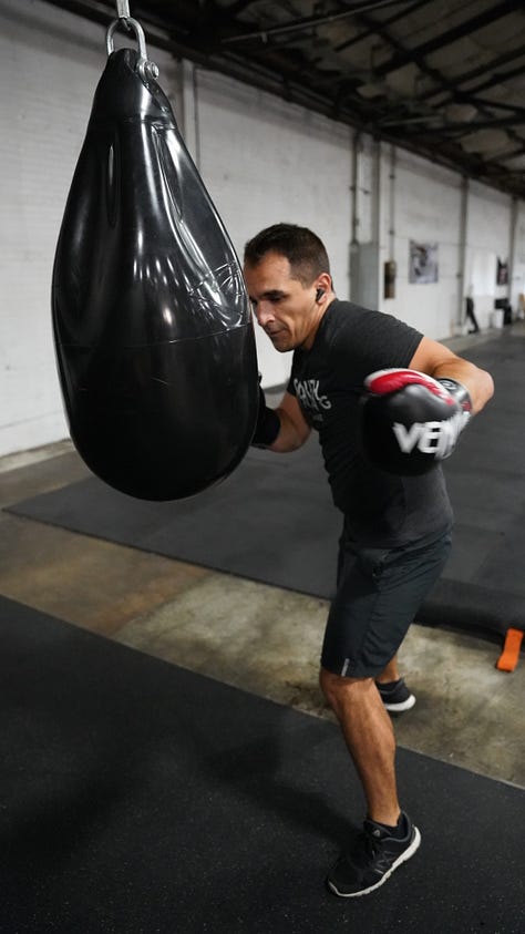 Brian hitting a punching bag at the back of a gym.