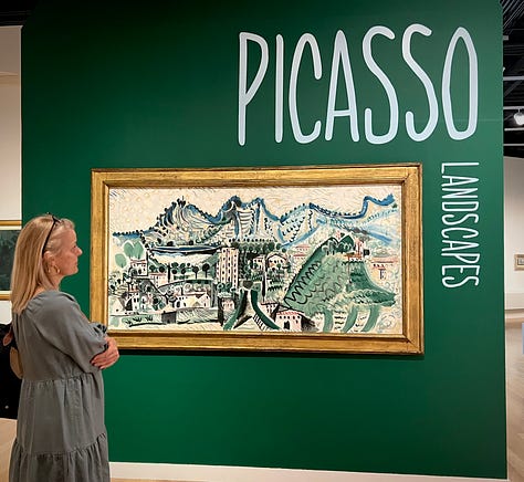 woman looking at a Picasso landscape, "The Village of Vauvenargues." Photograph of Picasso in his studio, and a display showing (R-L) Pablo Picasso, Luis Miguel Dominguin and Paulo Picasso