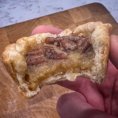 Three photos from left to right. First, the remains of the peach-blueberry pie in its pie tin. We can see the brown crumble top and the dark purple filling. Next, a hand holding a butter tart that has a bit taken out of it. we can see creamy golden filling and the dark pecans on top, as well as the slightly flaky pastry. Finally a baby pickle on a fork with a bite taken out of it. It... looks like a pickle with a bite taken out of it. Nothing special (just l like the flavour).