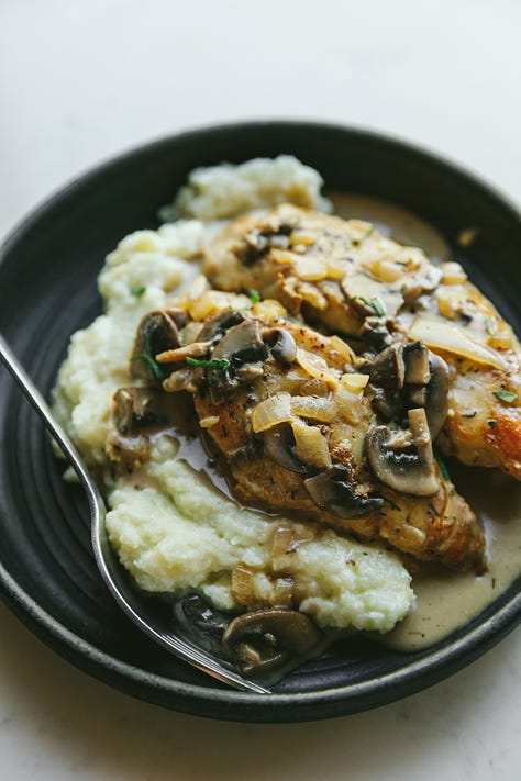 Creamy mushroom chicken in a skillet and on a plate with cauliflower mash.