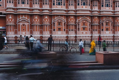 People rushing in the foreground of the Hawa Mahal.