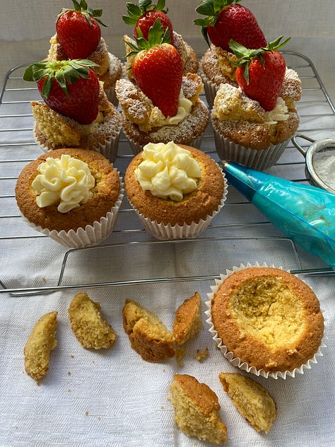 Filling strawberry Butterfly buns with buttercream and topping each of them with a fresh strawberry.  