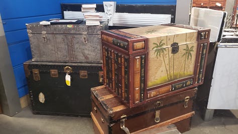 Pictures of random furniture, trunks, statues, lamps, stained glass windows, and a cart and fake cow from a warehouse that sells repurposed, salvaged items. 