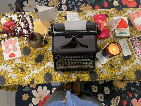 Typewriter set up on a card table in a bookshop and three index cards with haiku on them.