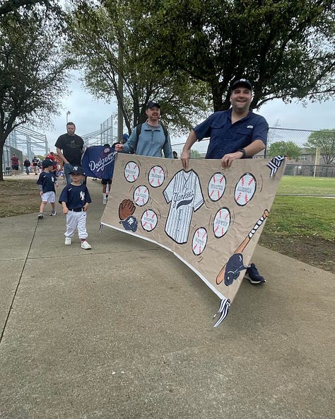 Little boys in baseball uniforms carrying banners bearing their names