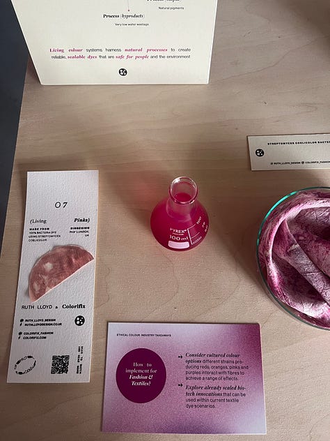 1-2. Exhibition table for 'pinks' from Ruth Lloyd and Colorifix showing fabric samples in petri dishes dyed directly with bacteria, and a vial of bacterial culture; 3. Pink bacteria-dyed fabrics hung up in the exhibition space with other brightly-coloured fabrics in the background.