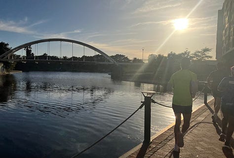 Canal on the left of the path, runners ahead on the course