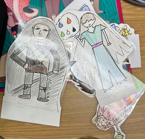Images of characters drawn by students, cut out of paper, laminated and mounted in air dry clay so they stand up. 