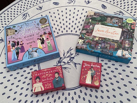 The boxes for "The Jane Austen Game," "The World of Jane Austen" puzzle, "Matchmaking: A Jane Austen Memory Game," and "Jane Austen Playing Cards." Image 2: The game board during a round of play for "The Jane Austen Game." The many pieces are assembled on the board. Image 3: The Emma Woodhouse character board and character cards during a round of play of "The Jane Austen Game." Image 4: Cards from both "Matchmaking: A Jane Austen Memory Game" and "Jane Austen Playing Cards" are spread out on a table next to "The Jane Austen Game" and "The World of Jane Austen" puzzle. Image 5: A close up of the cards from "Matchmaking: A Jane Austen Memory Game" 