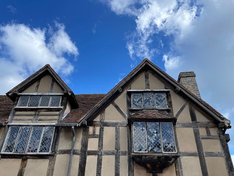 Old Tudor house with wood beams, old windows against a blue sky; swans and ducks on the River Avon; The old public librabry in white and wood Tudor style; The Royal Shakespeare Theatre; The Pen and Parchment pub with sign hanging, windows and flowers 