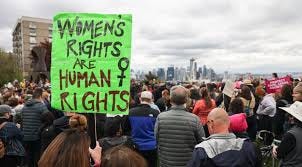 Colourful images of women from Pacific, India, Africa and the US at women's right protests with banners and placards featuring the women's sign as well as badges, singlets and posters with the same symbol. 