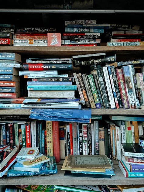 First image: A boat moving through water toward an opening in a gate. Image two: A bookshelf packed with various books. Image three: Overhead view of a wooden serving tray with a burger, cup of ketchup, and fries.