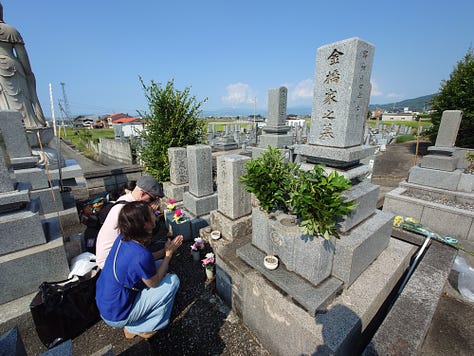 9 pictures of Jackson, his wife, his Japanese cousin, Eikichi, and Eikichi's wife, Megumi, together, visiting the ancestral grave in Iyo City, walking around Matsuyama, eating dinner with Uncle Kazuya, leaving the train station, eating Oden in Ginza, posing with Lin-Chan, the Japanese poodle, and pictures of Jackson and Erika taking pictures of the Tokyo skyline