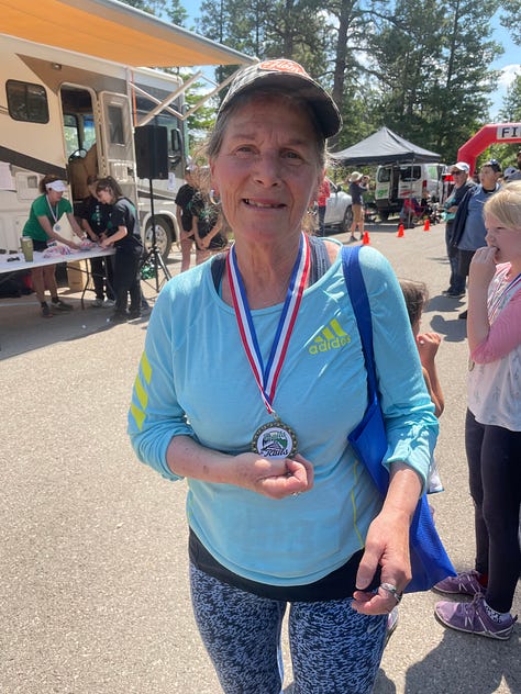 finish line posing photo, an older woman in a blue shirt holds a medal, and a group of people in christmas pajamas pose in the park, fun run, Cloudcroft, New Mexico