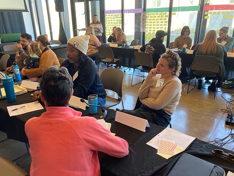 First two photos include Deschutes assembly members deliberating in small groups, and the third photo has a women looking at a wall with priorities that have been written up.