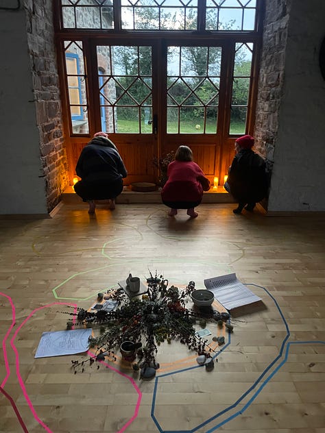 L-R: a white house with blue accents at sunset with lawn in front, three white women crouching with their back to camera, slighting candles, with a mandala or flowers behind them, a Black woman's hands crafting a cardboard loom for weaving, 6 white women in a barn sitting in a circle around dried flowers and candles with a roaring fire to the right, 11 women standing in a circle on a lawn, women sitting in a semi-circle around a mandala of flowers, with taped circles on the floor and post-it notes