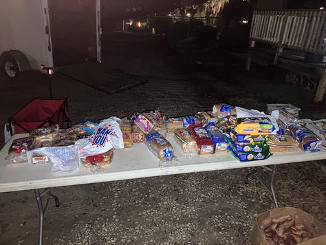 Jon Pantoja, Edward Hood, Daniel Paasch, and Ginni Stalker stand in front of their food distribution tables