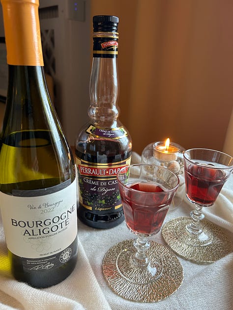 French wines and fruit syrups for making a kir cocktail, along with bottles and glasses