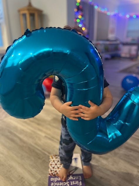 toddler holding blue nyon 2 balloon, 2nd birthday cake, a snippet from FURY, snow falling near a street lamp, kids looking at snow through the window, snow