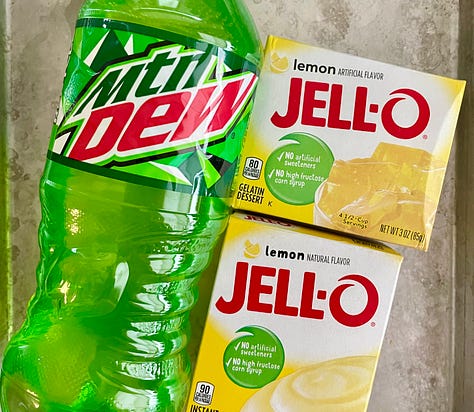 a green bottle of Mountain Dew with yellow boxes of Jello lemon gelatin and lemon pudding mixes, and sliced banana with pineapple chunks