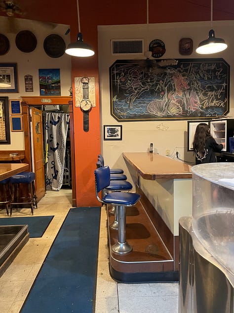 Inside Emmett's Oyster Bar in Seattle. Blue and white checkered table cloths, oysters, interior signage, and a sleeping dog. 