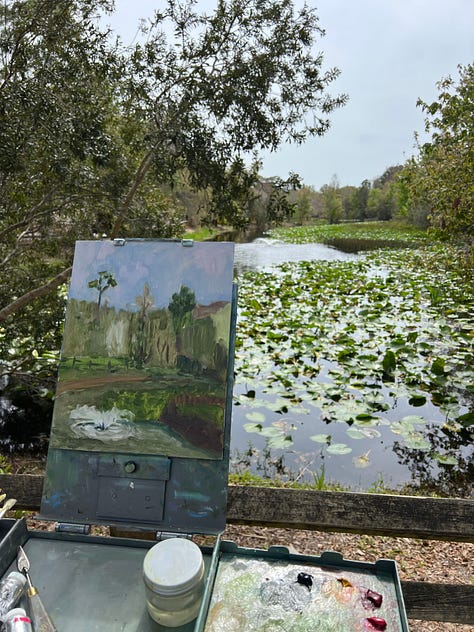A man paints a swamp and marsh scene inside a botanical garden, which included baby aligators.