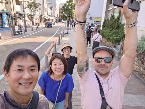 9 pictures of Jackson, his wife, his Japanese cousin, Eikichi, and Eikichi's wife, Megumi, together, visiting the ancestral grave in Iyo City, walking around Matsuyama, eating dinner with Uncle Kazuya, leaving the train station, eating Oden in Ginza, posing with Lin-Chan, the Japanese poodle, and pictures of Jackson and Erika taking pictures of the Tokyo skyline