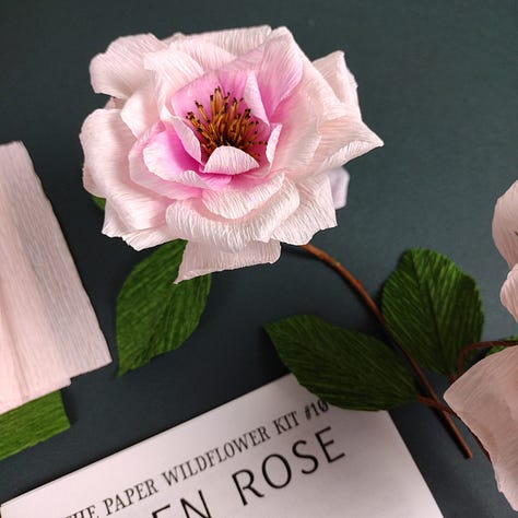 Three images of the new open Rose CraftKits showing the contents of the kit, paper, wire and instructions, plus the finished roses, very pale pink with a darker pink centre, a dark brown stem and deep green leaves.