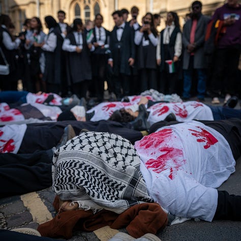 people wearing white t-shirts with red handprints on them lie on the steps outside the Sheldonian building in Oxford as others queue up in academic gowns. photos courtesy of @madeleine_observes