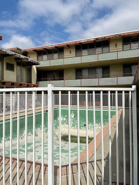 2040 Rodney Avenue, a midcentury modern apartment complex that has been empty for years and is suffering from deferred maintenance (mold, stucco damage, peeling paint, a long-empty pool, cracked concrete, rust stains, etc.).