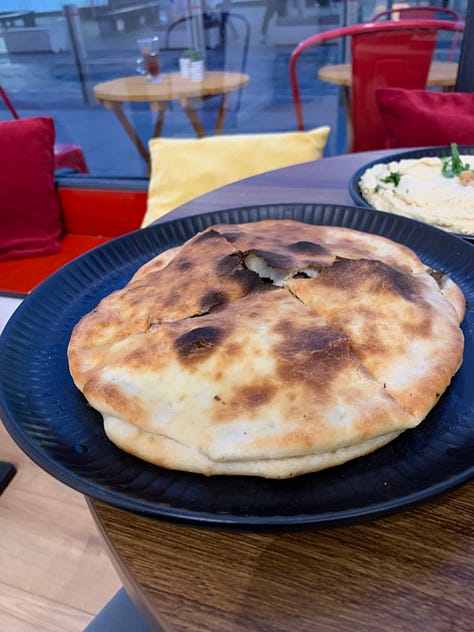 Pitta bread with humus, a toasted pitta and a plastic cup with juice