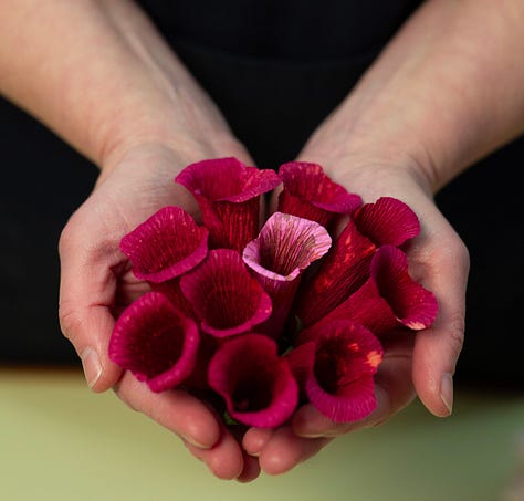 Pink paper foxglove, a handful of foxglove florets, a finished paper foxglove with pink and purple painterly florets.