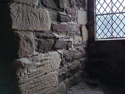 Photo of square open oven set in stone wall; Lines carved into stone wall from a distance, and close up